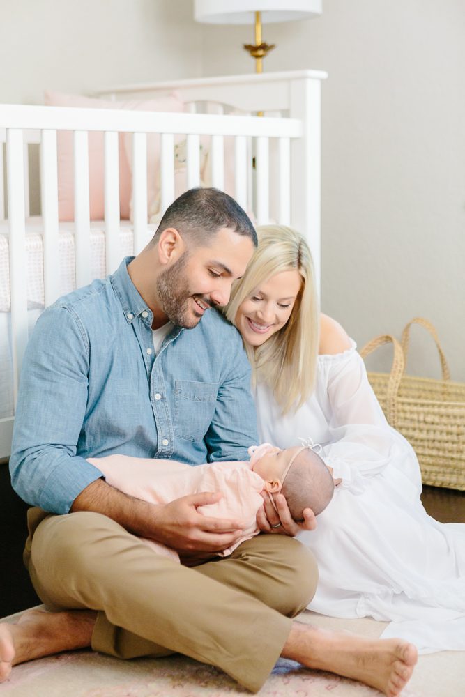 Mom and dad with newborn baby girl in light pink swaddle