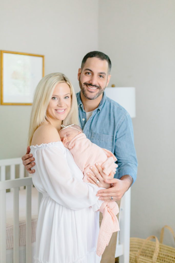 Mom and dad with newborn baby girl in light pink swaddle