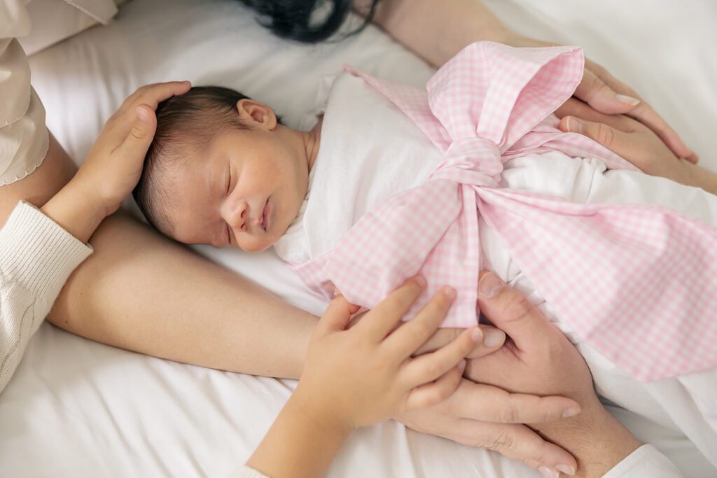 Light and airy newborn photography session in Tallahassee, FL, with a peacefully sleeping baby in soft wrapping.